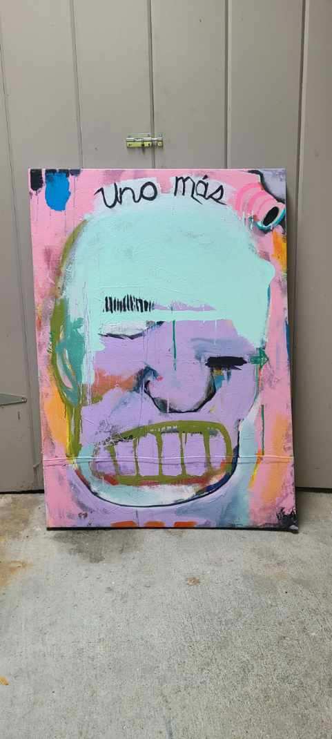 Large pink and blue painted face with Uno Más text